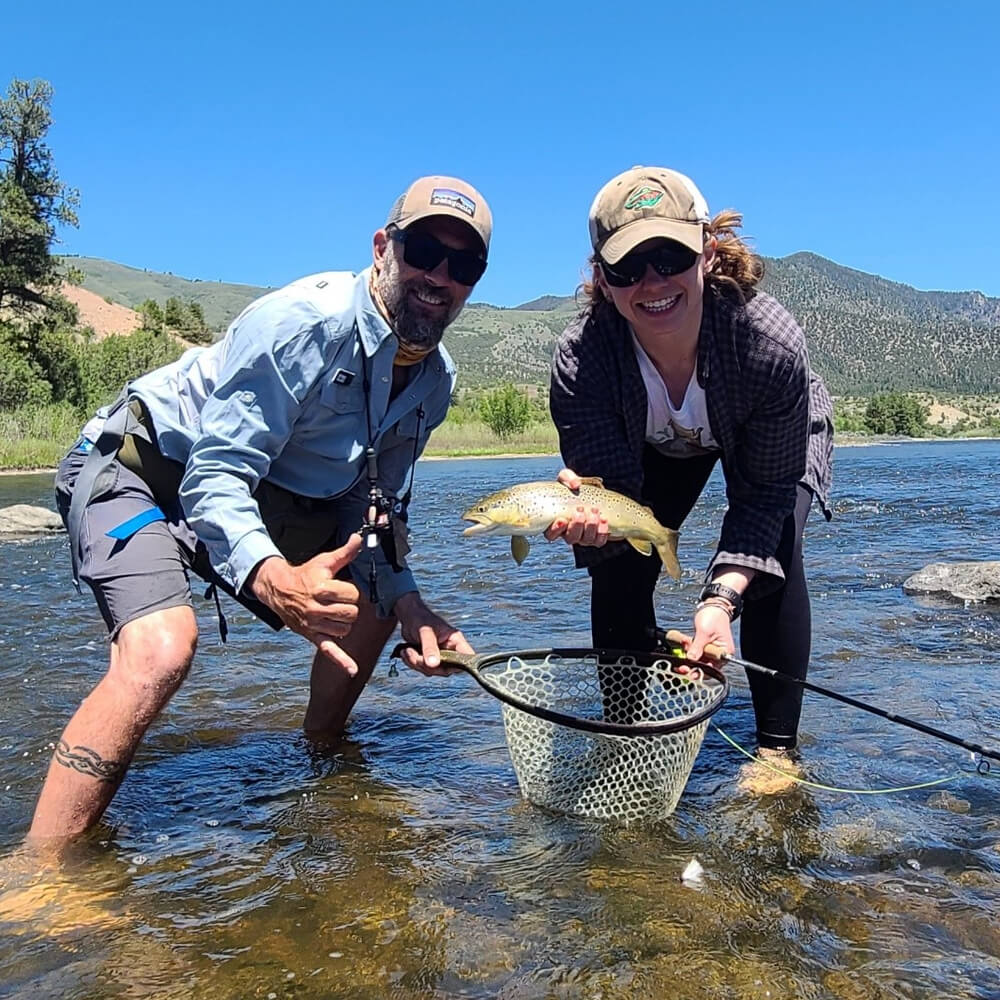 fly fishing guide with female quest holding a brown trout