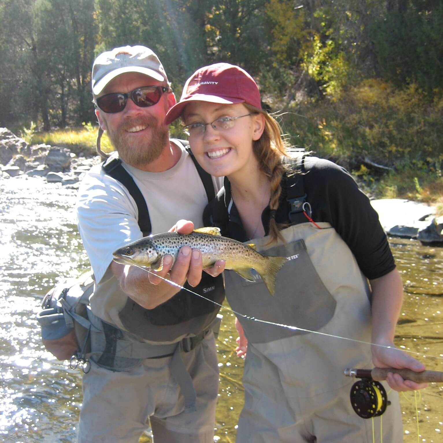 father and daughter fly fishing guests with a trout on in the fathers hand