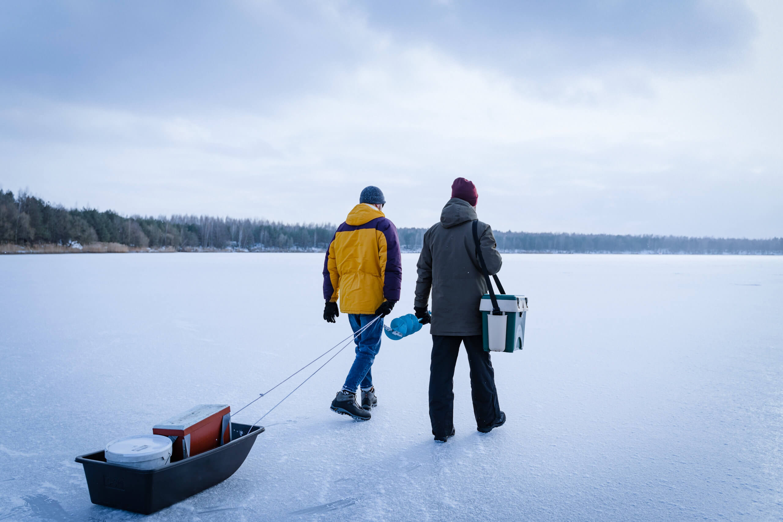 Two men walking on a frozen lake on their way to start ice fishing