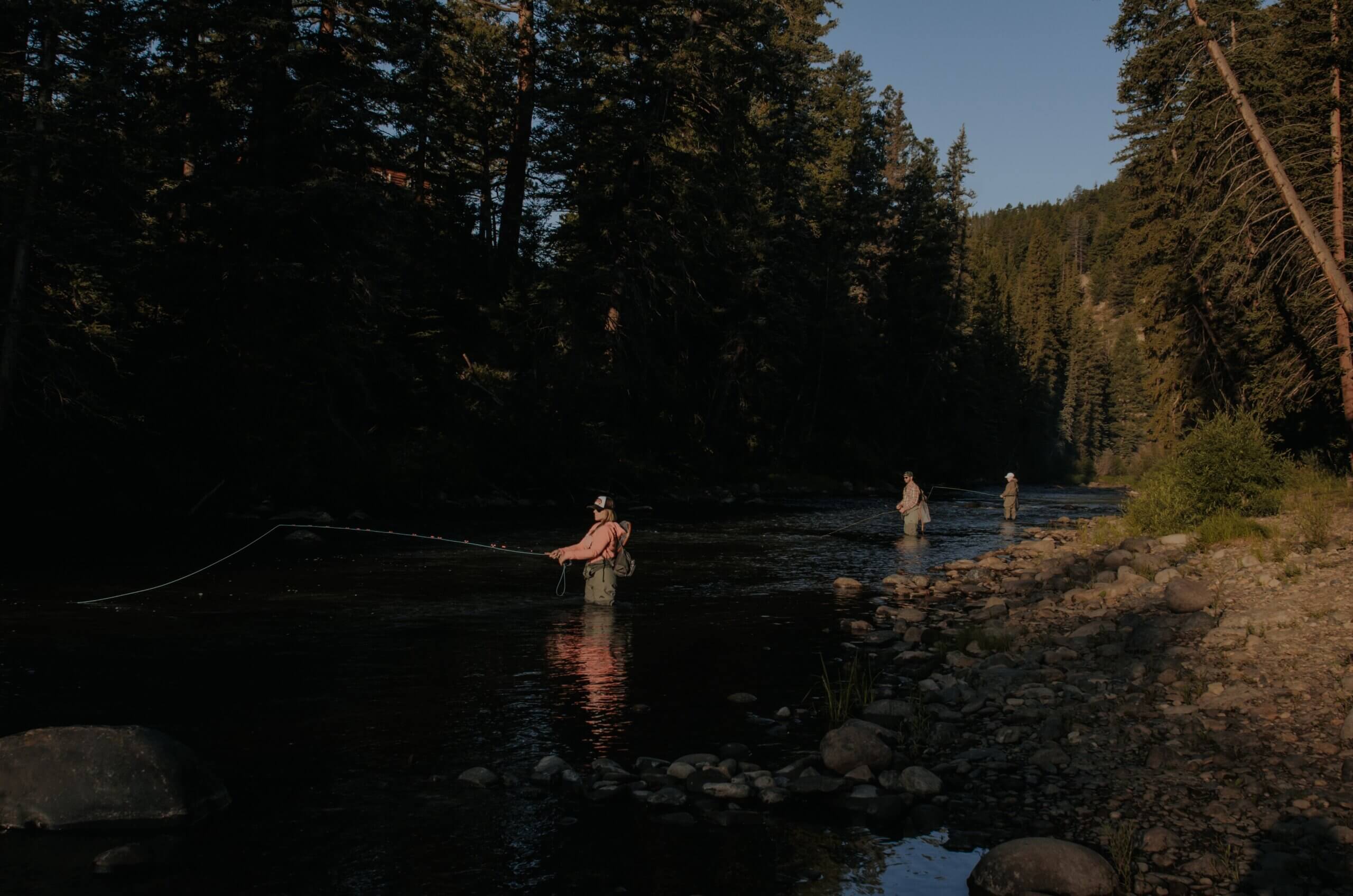 3 people fishing on a river