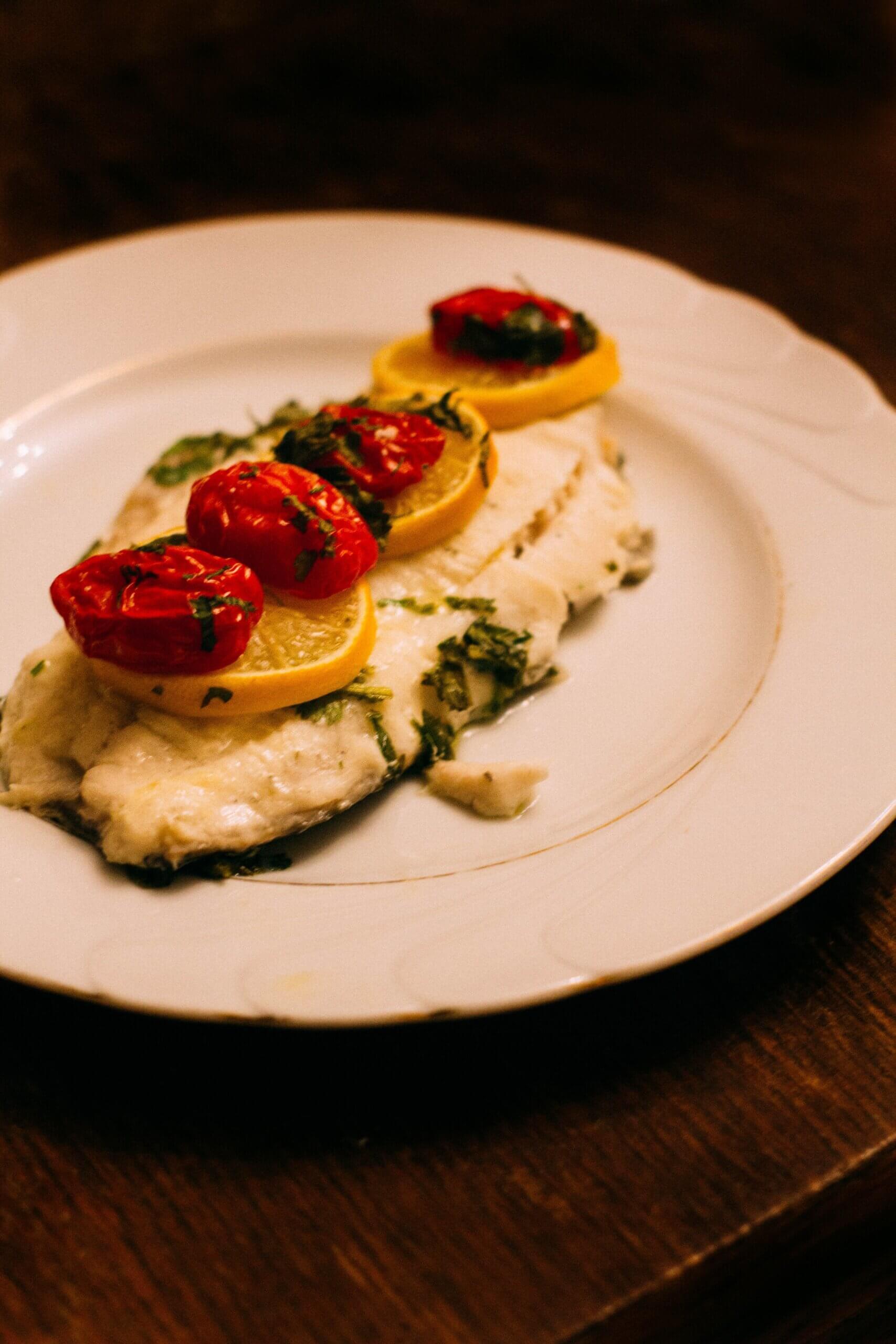 fish topped with lemon and tomatoes